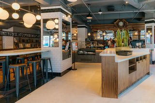 Caffe Vita's Smith Tower cafe featuring baristas behind the counter, a pastry case, and menu in front of mirrors.