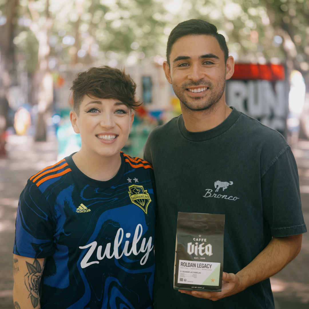 Sam Spillman and Alex Roldán smiling holding a 12oz bag of Roldán Legacy