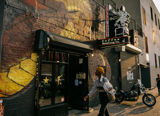 Outside of Caffe Vita's Bushwick location featuring a snake mural, neon sign, and customer walking by.