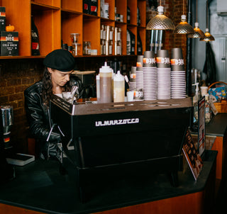 Barista making drinks behind espresso machine at the LES cafe