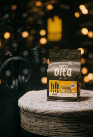 12oz bag of KEXP Blend front, sitting on stool with headphones and lights in background