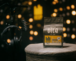 12oz bag of KEXP Blend front, sitting on stool with headphones and lights in background