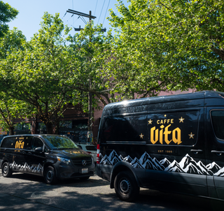 Parked Vita service van and Vita delivery van in front of buildings and trees