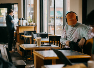 Caffe Vita's Fremont cafe featuring a customer at a table with iced latte, ipad, and headphones.