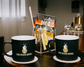 Caffe Luna singles on tray with The State Hotel mugs and coasters