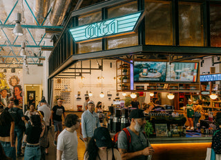 Caffe Vita's KEXP cafe featuring various customers and a view of the espresso machines and digital menu screens.