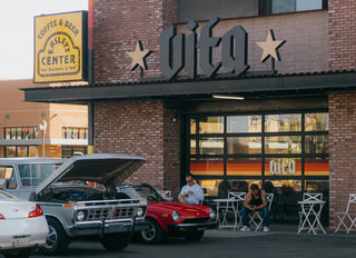 Outside of Caffe Vita's Phoenix cafe featuring Vita signage, Easley's Center sign, various cars, and customers.