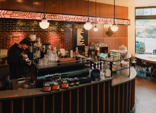 Caffe Vita's Sunset Hill Fiore cafe featuring a barista pouring milk behind an espresso machine.