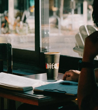Customer at cafe table with Vita branded cup on table with clipboard, pen, and paper