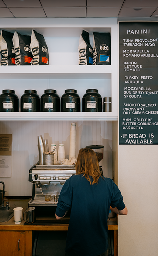 Barista making drinks in front of espresso machine at a Vita wholesale customer cafe