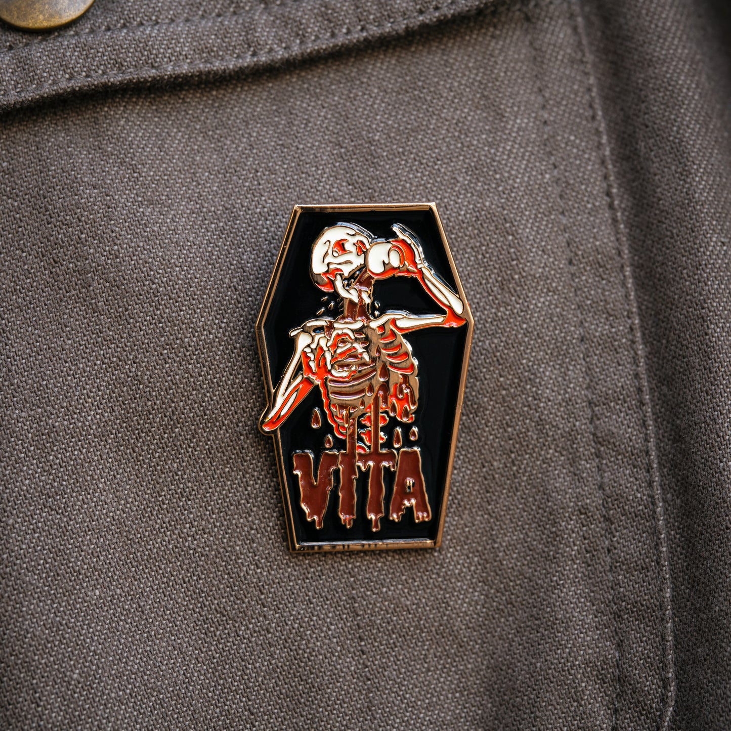 Image: skeleton enamel pin on jacket pocket. 