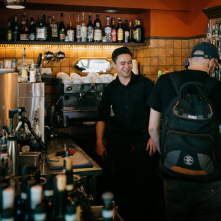 Caffe Vita service team member doing maintenance on an espresso machine in a wholesale customers' cafe.