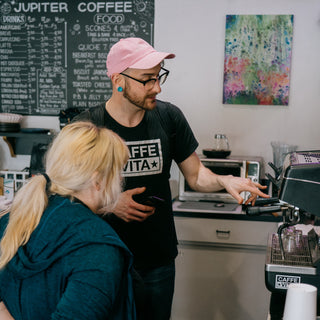Caffe Vita service team member giving an explanation of an espresso machine to a wholesale customer in their cafe.