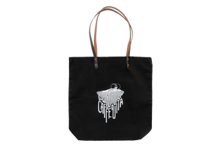 Black canvas tote bag with brown leather straps featuring white graphic design of spilled coffee forming the words 'CAFFE VITA'