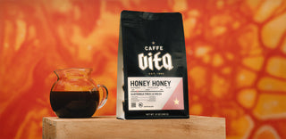 Honey Honey 12oz bag with brewed coffee in clear pitcher. Sourced from a women-led farm in Guatemala. Tasting notes of raspberry, white grape, honey.