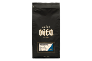 A black stand-up coffee bag with a resealable zipper, featuring the Caffe Vita logo in gold and a Moon River flavor label near the bottom,