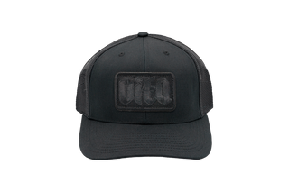 Black trucker hat with black mesh back and square black patch with Vita logo