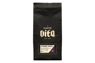 A black stand-up coffee bag with a resealable zipper, featuring the brand name 'The Caffe Vita' in gold and white lettering, and a 'Strange Magic' flavor label near the bottom. 